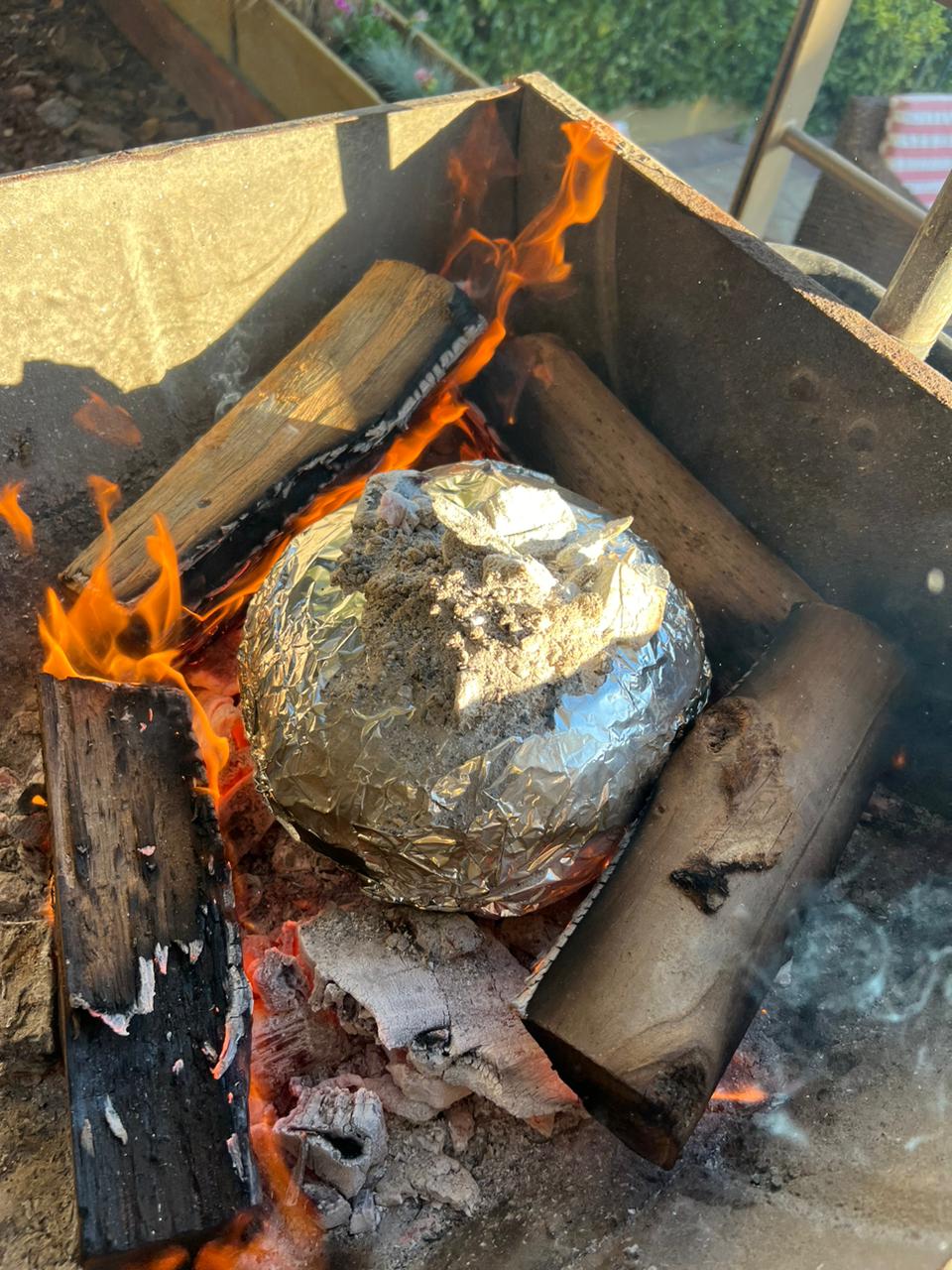 La calabaza envuelta en aluminio entre las brasas, durante la cocción